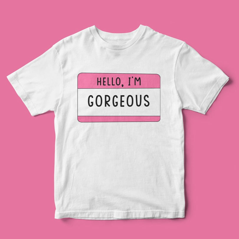 The "Hello, I'm Georgios" White T-shirt offers a stylish look with a pink tag graphic reading "Hello, I'm Georgios" on a soft pink background, providing premium comfort and making a bold statement wherever you go.