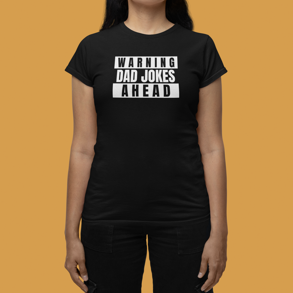 'Warning Dad Jokes Ahead' women's tee in black, woman wearing it on orange backdrop, funny humor gift