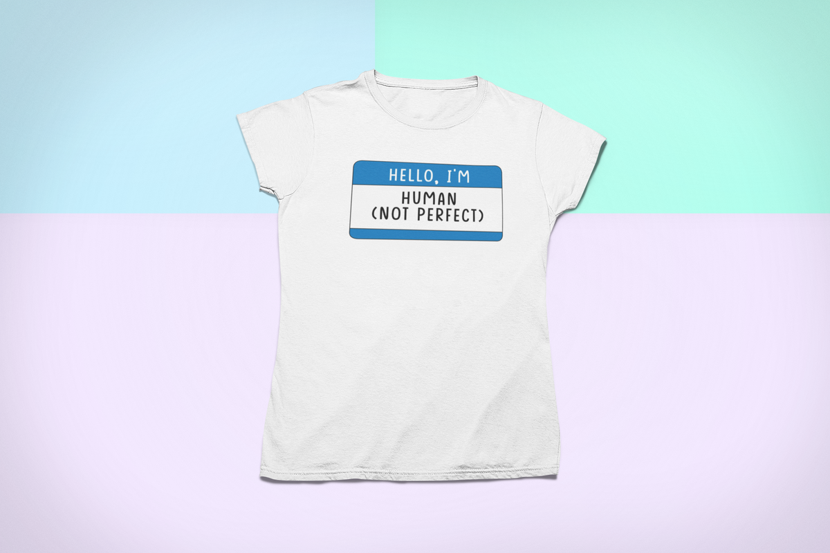 Hello I'm Human Not Perfect name tag T-shirt in white, flat lay on pastel background, motivational tee