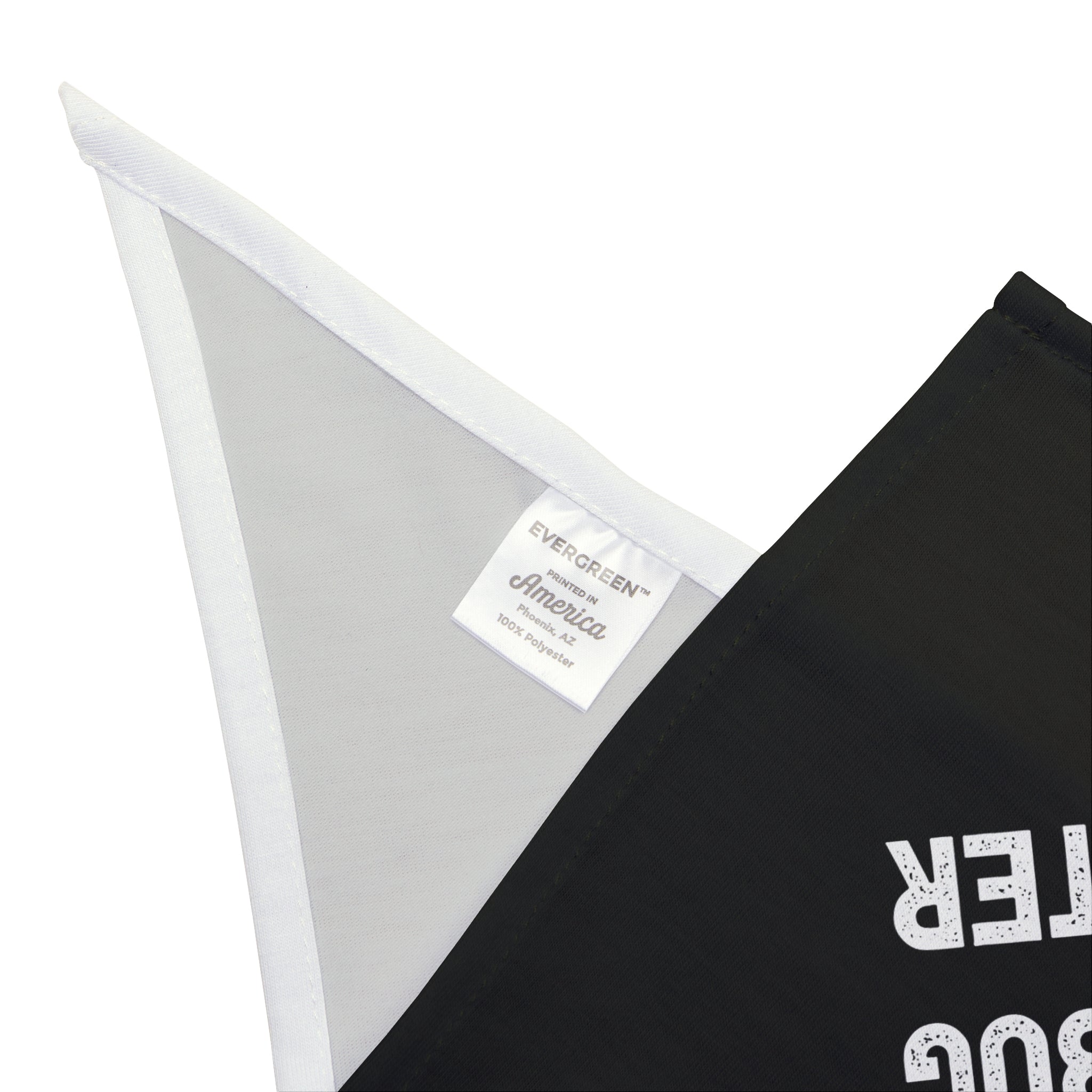 Close-up of a fabric label on a garment, displaying the brand name "Evergreen America," followed by "100% soft-spun polyester." A portion of black fabric is visible with partial lettering, as stylish pets might wear in the trendy "Deploy Now, Debug Later - Pet Bandana.