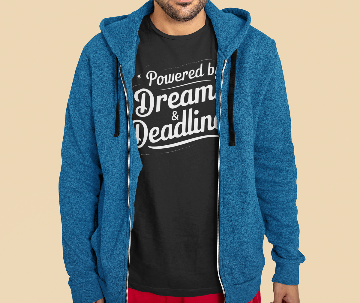 'Powered by Dreams & Deadlines' organic t-shirt in black, man wearing it under blue hoodie, coder gift