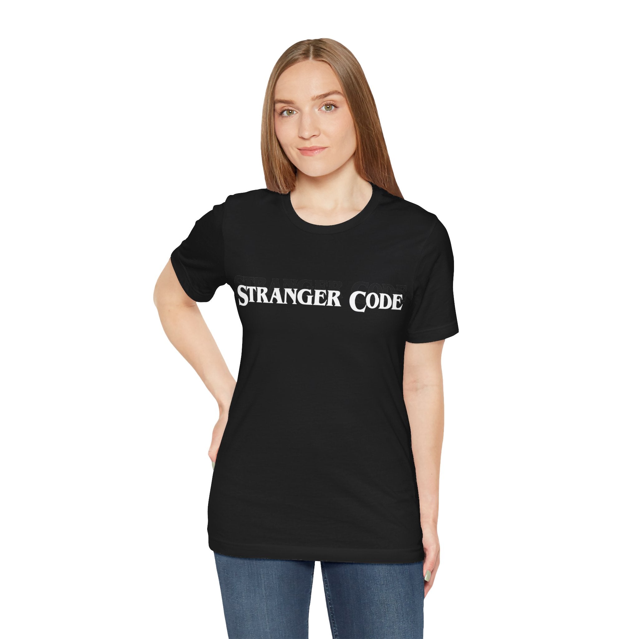 A person standing against a white background is wearing the "Stranger Code Tee Shirt," made from soft cotton for comfort.