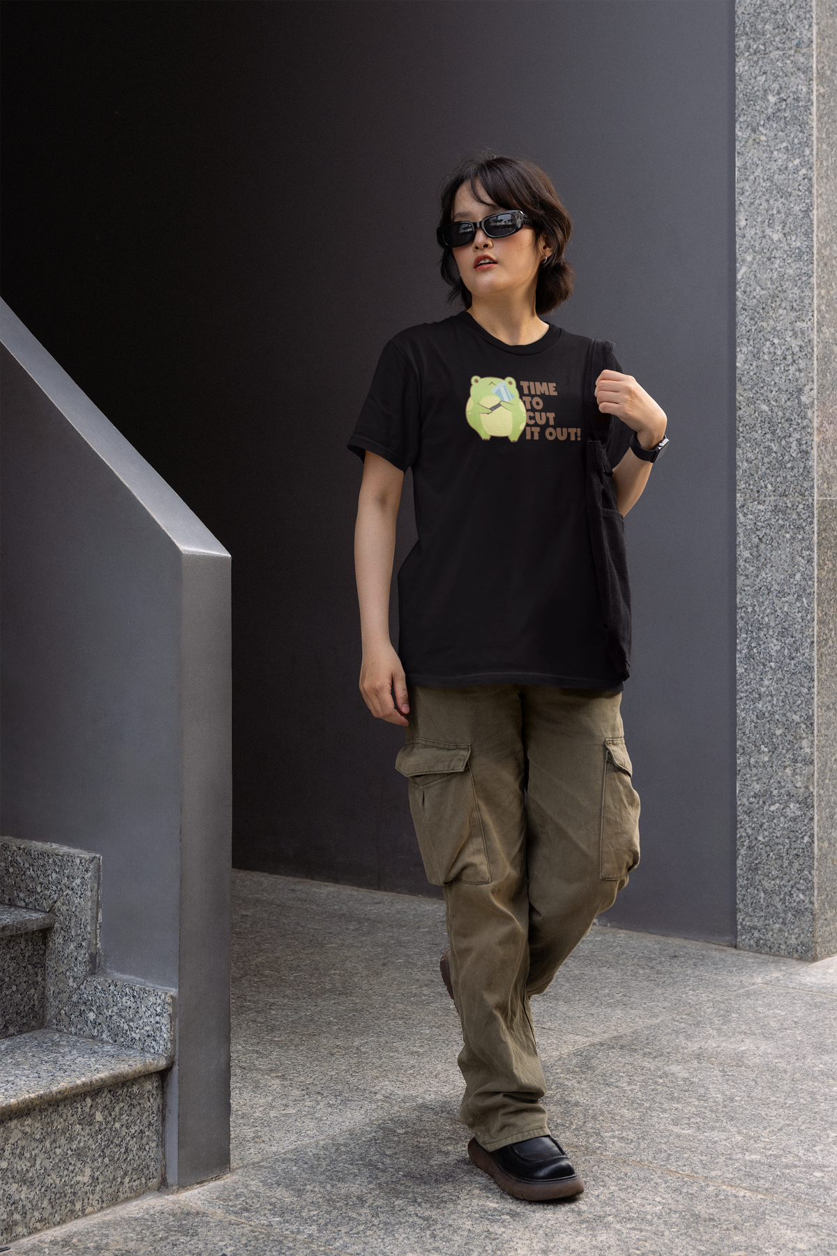 'Time to Cut It Out' frog women's tee in black, man wearing it on stairs, funny science pun gift
