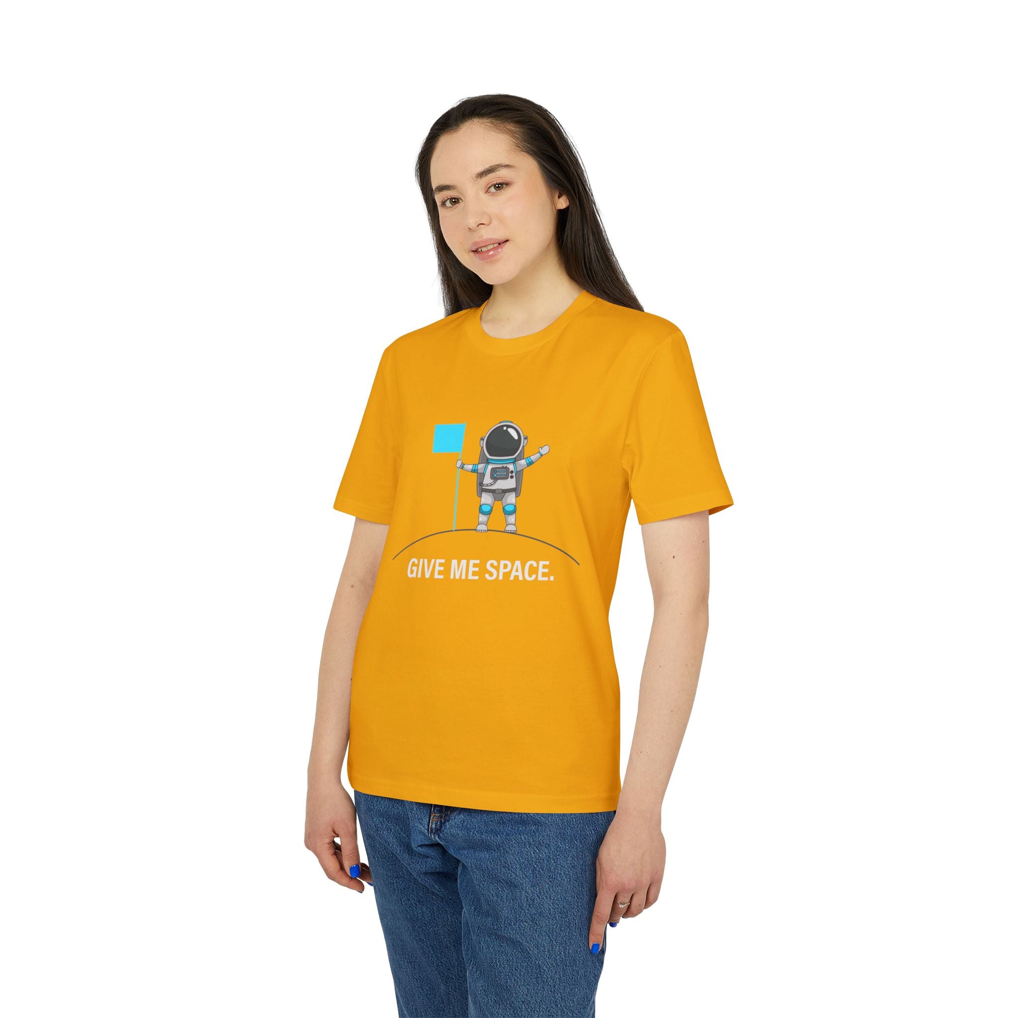A woman wears the "Give me space - Organic T-Shirt," a yellow shirt with a cartoon astronaut and the phrase "GIVE ME SPACE," standing against a white background.