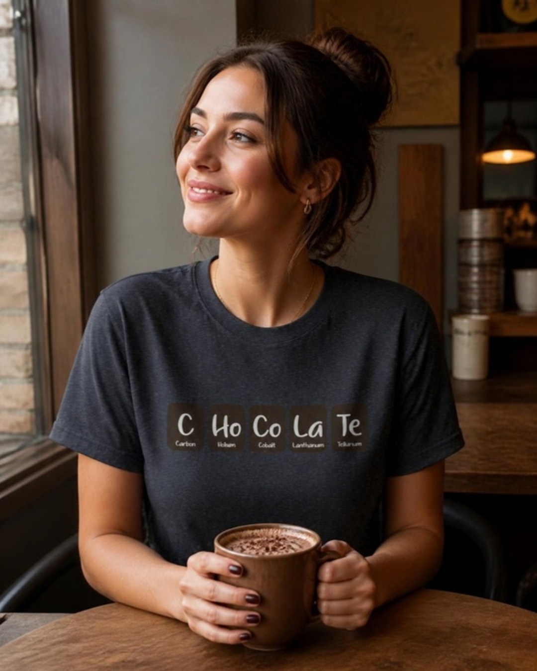 C-Ho-Co-La-Te tee in dark grey, woman in a cafe holding hot chocolate, chemistry pun gift