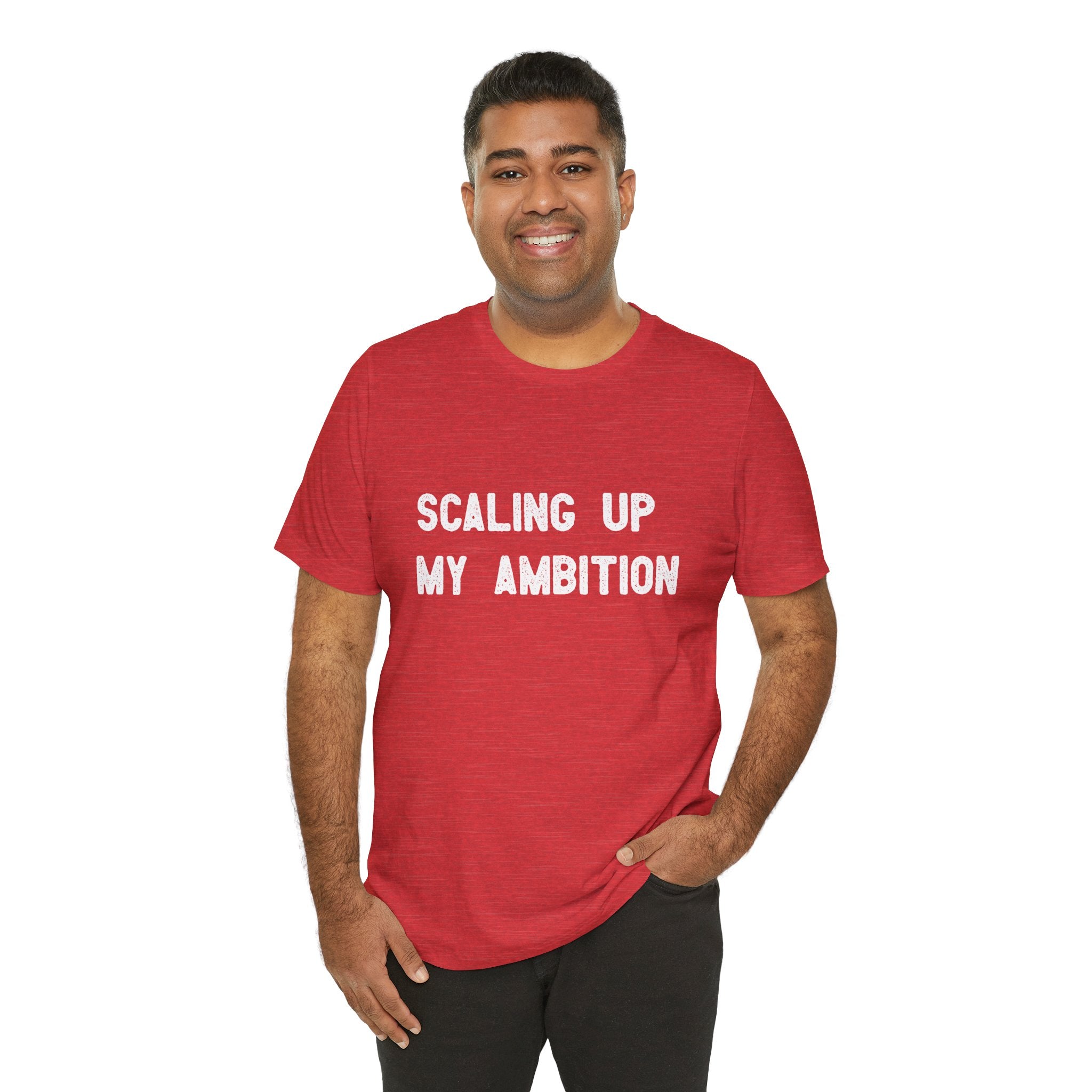 Dressed in the "Scaling Up My Ambition" T-shirt crafted from durable Airlume cotton, the person stands smiling with the bold message across the front, one hand casually resting in their pocket.