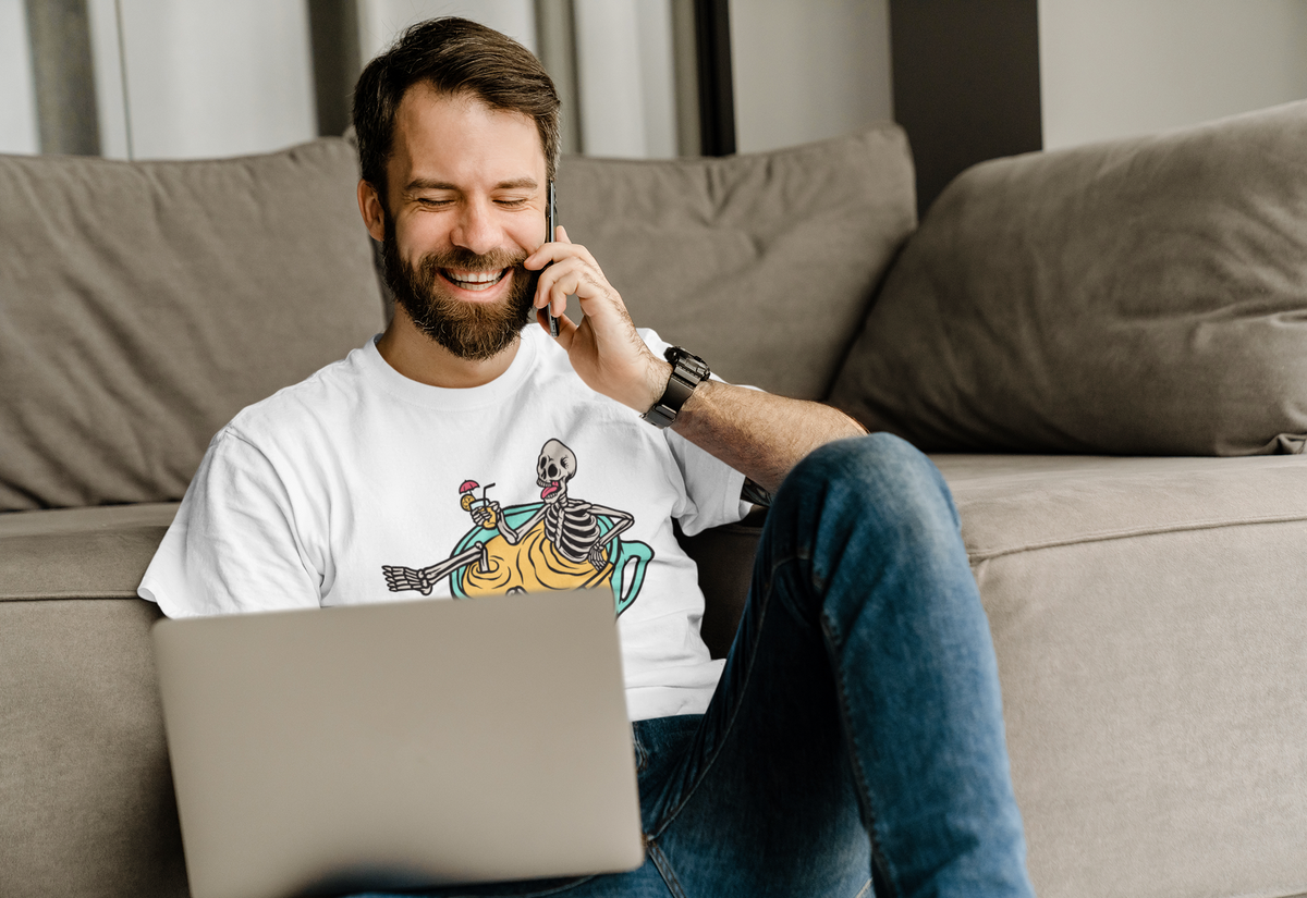 'Relaxing Skull' t-shirt in white, man wearing it on the couch with laptop, funny coffee lover gift