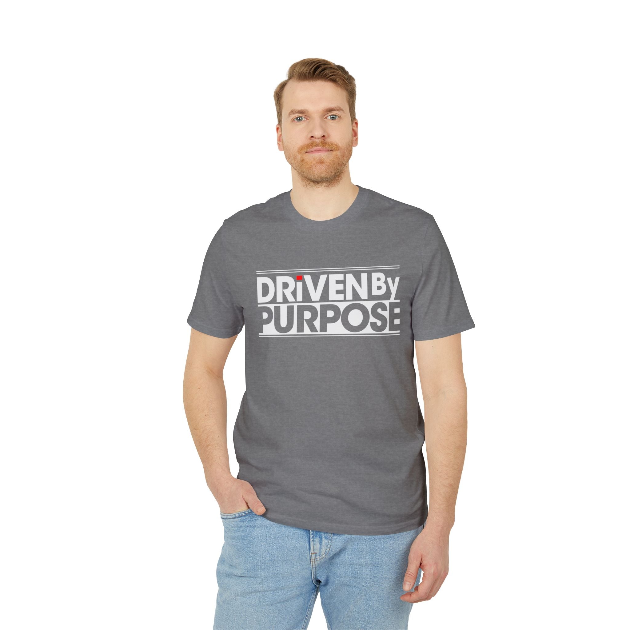 A man stands with one hand in his pocket, wearing the "Driven by purpose - Organic T-Shirt," an eco-friendly gray tee made from organic cotton with "Driven by Purpose" in bold white letters—ideal for conscious programmer essentials.
