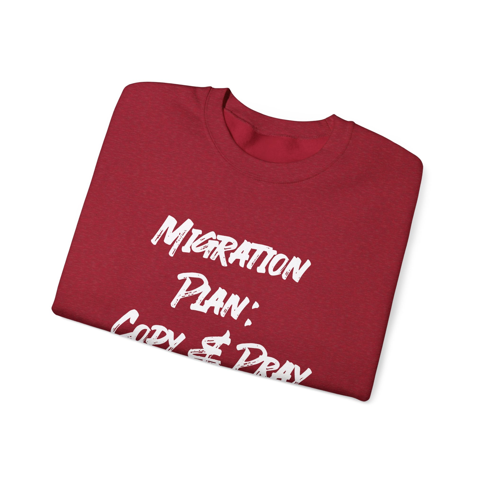 Red folded sweatshirt with white text, "Migration Plan Copy and Pray." Ideal for staying cozy during colder weather while making a bold statement.