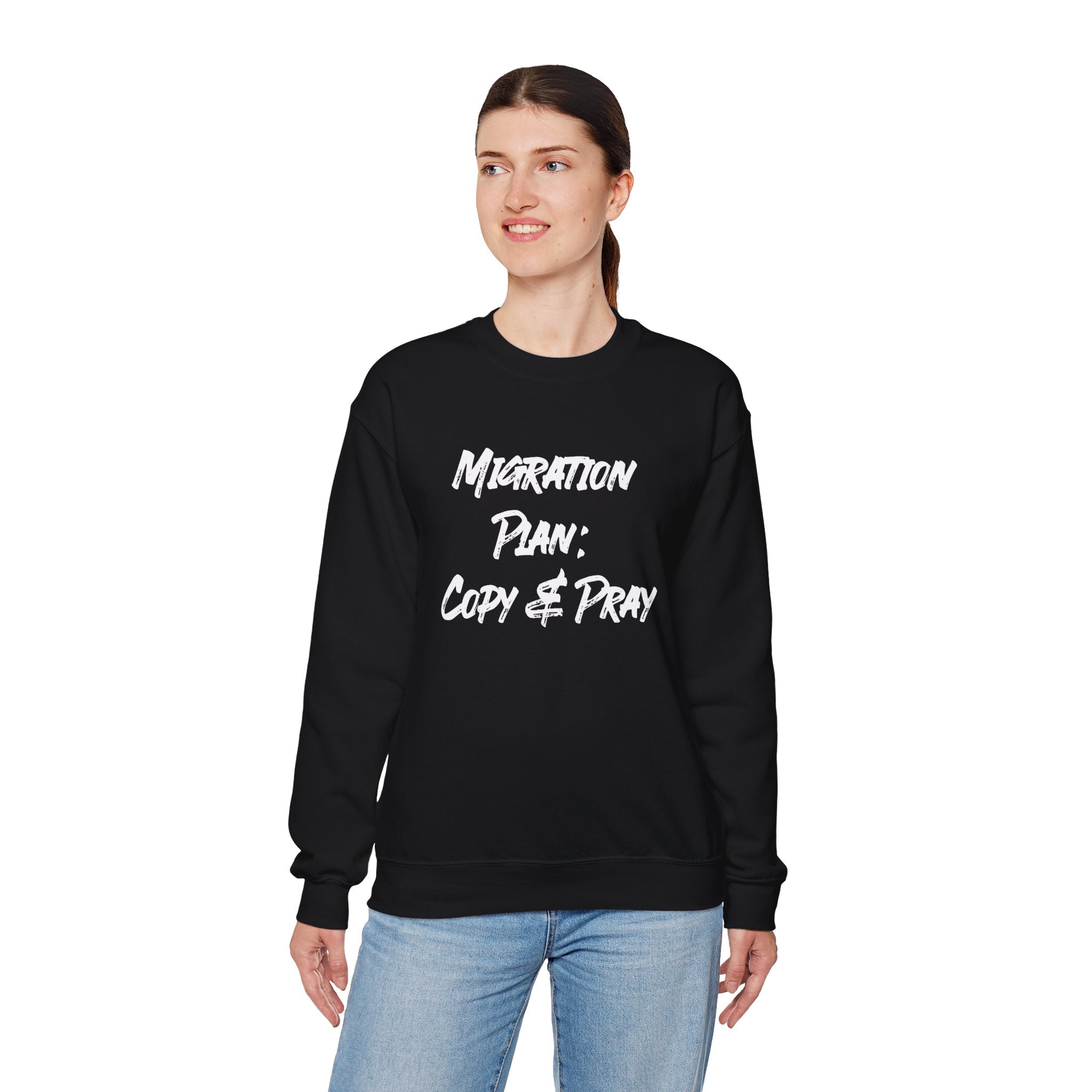 Against a plain white background, a person wears the cozy Migration Plan Copy and Pray sweatshirt in black, ideal for colder weather. The bold text "Migration Plan: Copy & Pray" highlights the witty design.