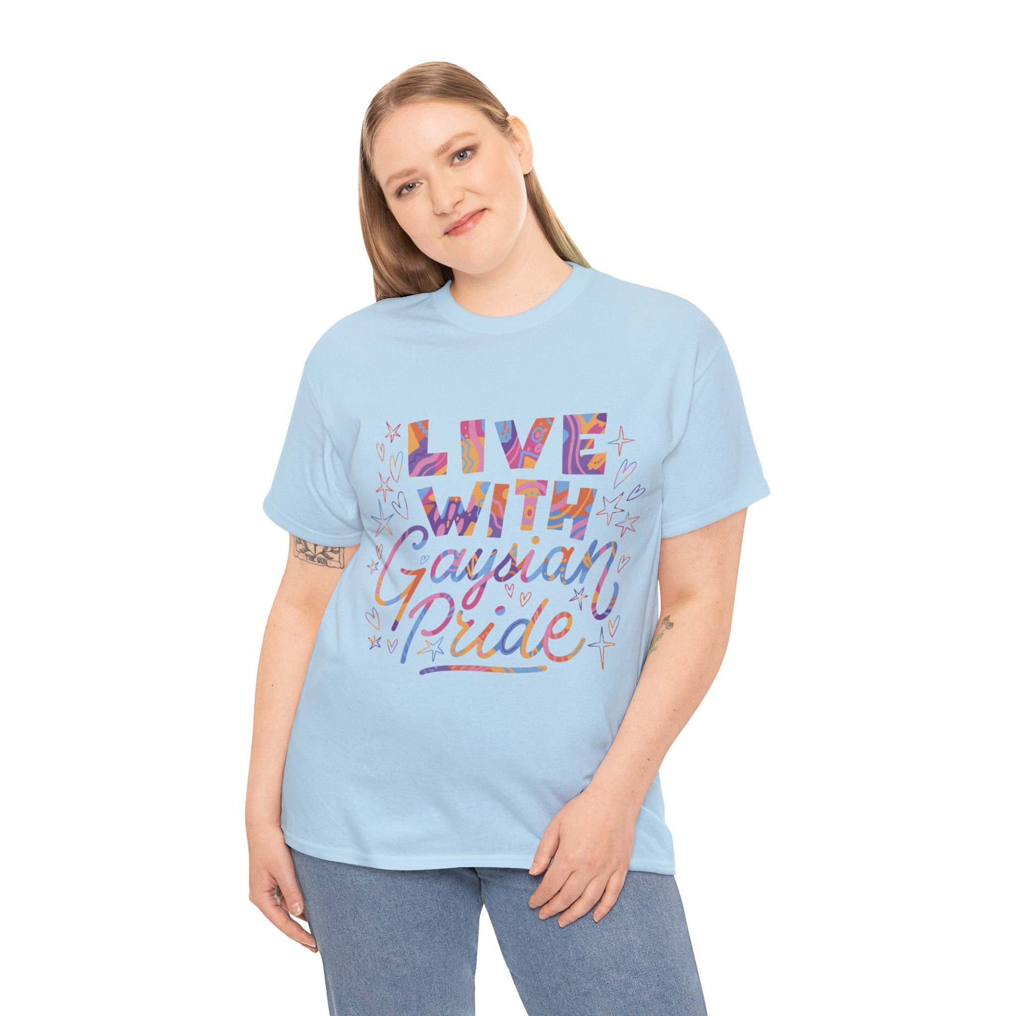 Against a plain white background, a person wears the "Live With Gaydian Pride" t-shirt in light blue. Their long hair frames their face, showcasing a blend of vibrant style and geeky charm.