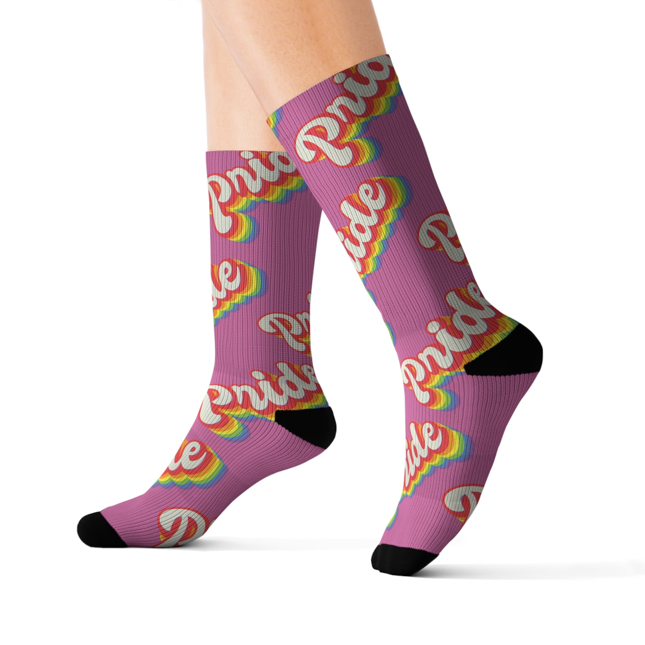 A person is wearing Pride Socks, which are high-quality with a sublimated print of "Pride" in rainbow colors, complemented by black toes and heels. These purple socks have cushioned bottoms for added comfort.