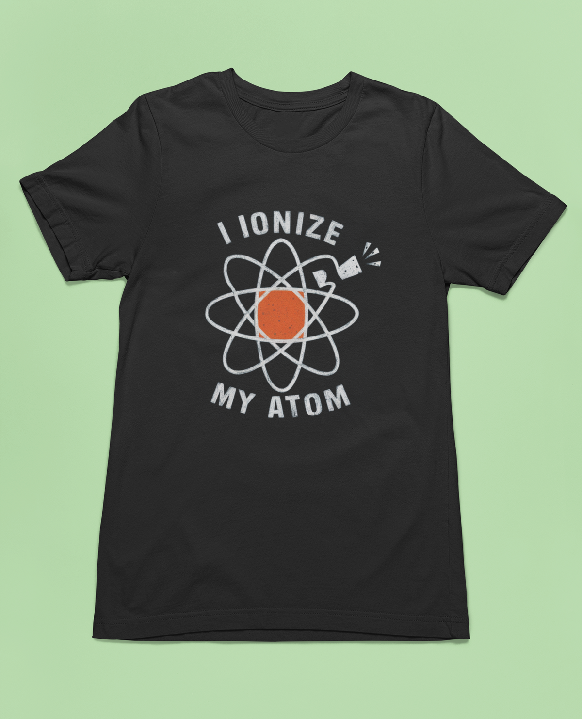 'I Ionize My Atom' t-shirt in black, flat lay on green background, funny science teacher gift