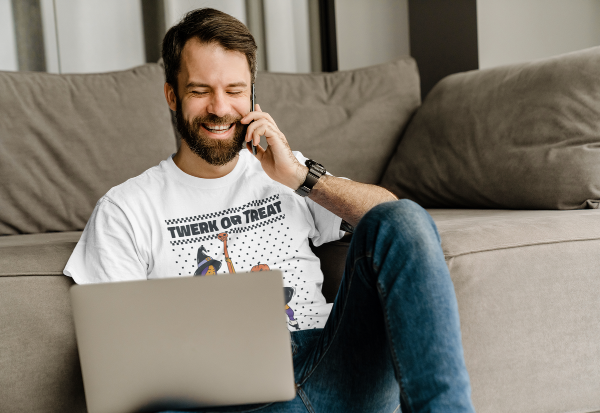 'Twerk Or Treat' t-shirt in white, man model wearing it while on the phone with a laptop