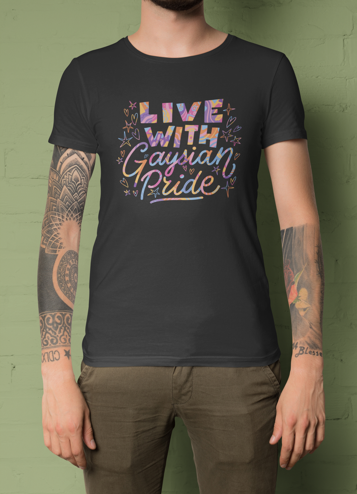 'Live with Gaysian Pride' T-shirt in black, man wearing it against a green backdrop, pride gift shirt