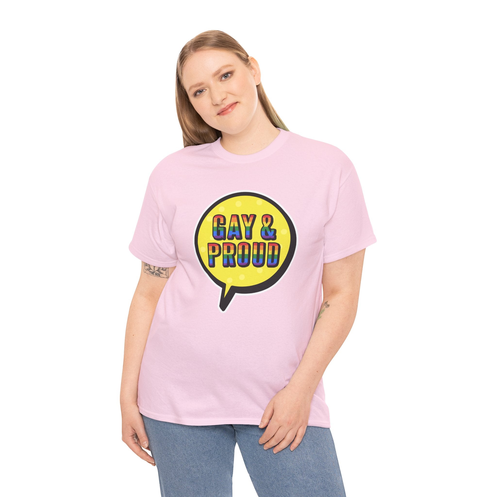 A person wearing the "Gay & Proud T-Shirt," a comfortable cotton tee in pink featuring a speech bubble design, stands against a plain backdrop. Ideal for everyday wear, this shirt makes a bold statement while keeping you comfortable.