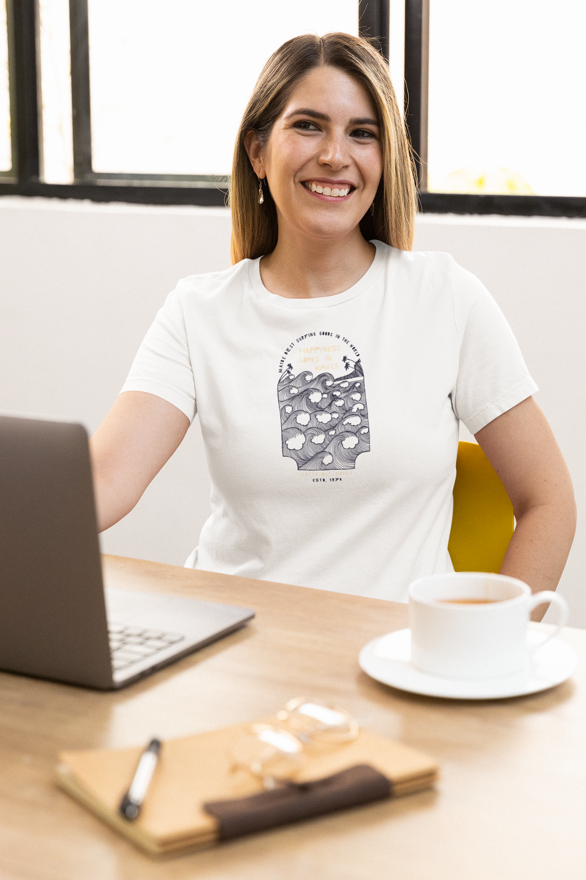 'Happiness Comes in Waves' t-shirt in white, woman wearing it at an office desk, T-Shirt mockup, Geekpsters