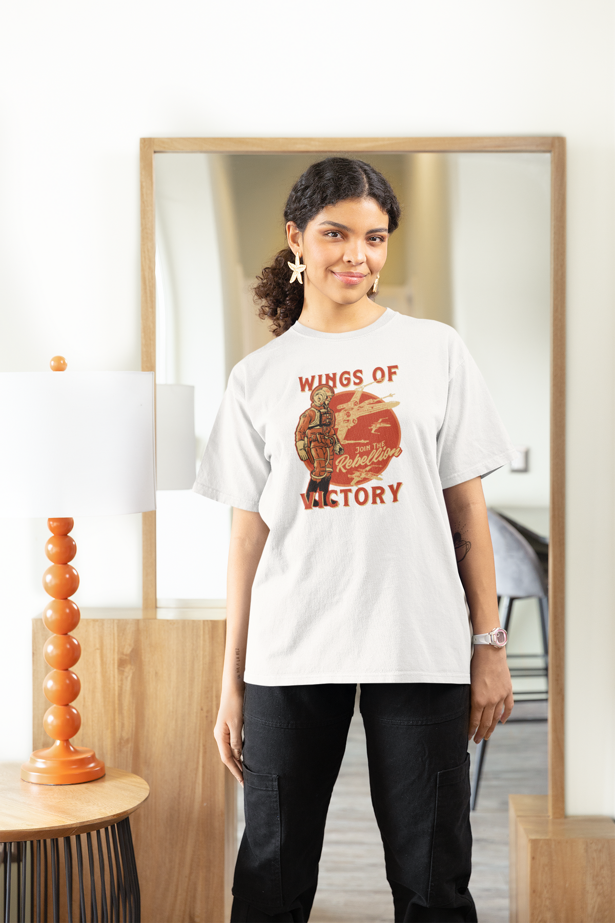 'Wings of Victory' women's tee in white, woman wearing it at home, rebel warrior graphic tee gift