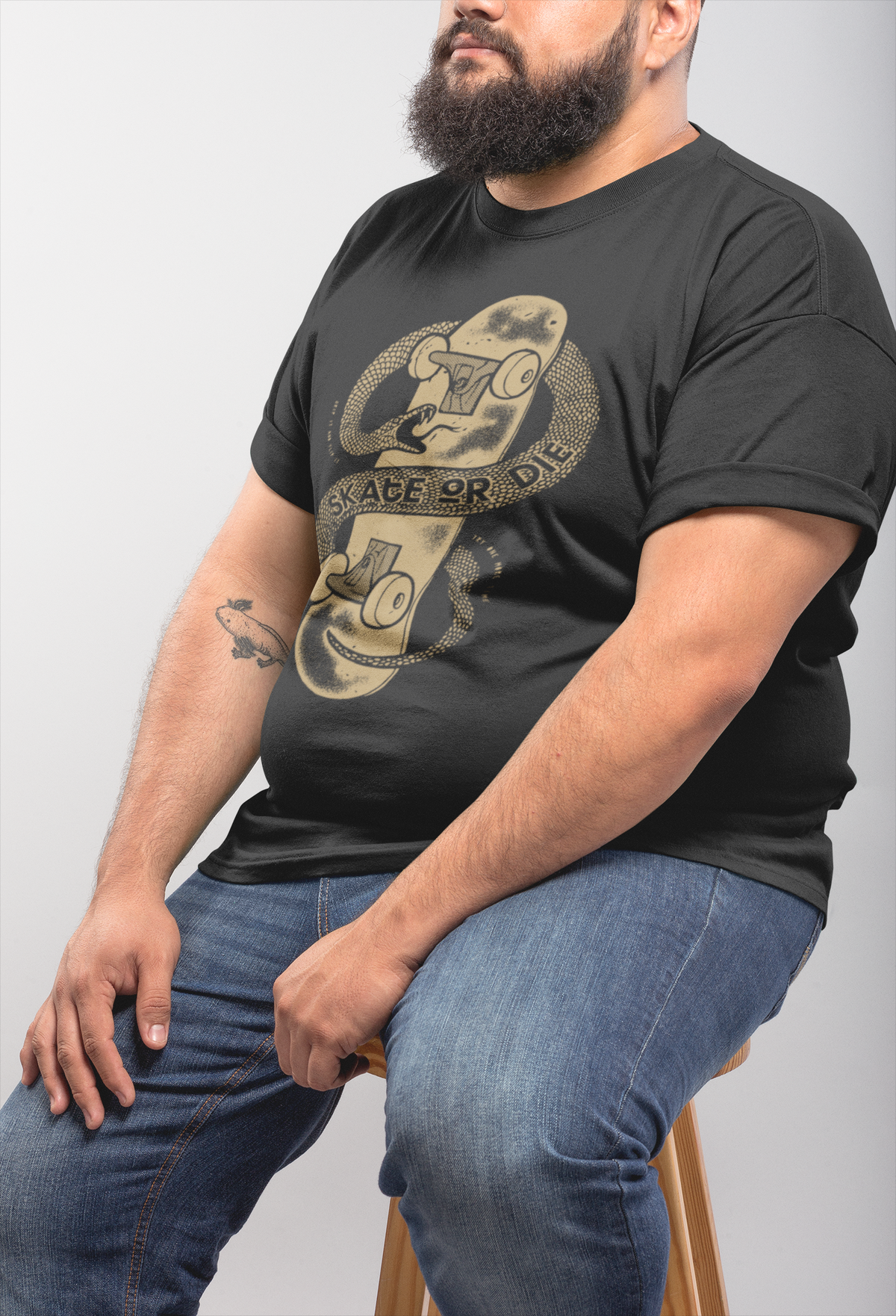"Skate or Die" t-shirt in black, bearded man wearing it seated, edgy gift for skateboarders
