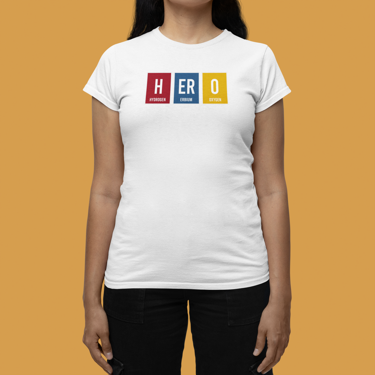 'HERO' periodic table t-shirt in white, woman wearing it, mustard backdrop, science pun tee