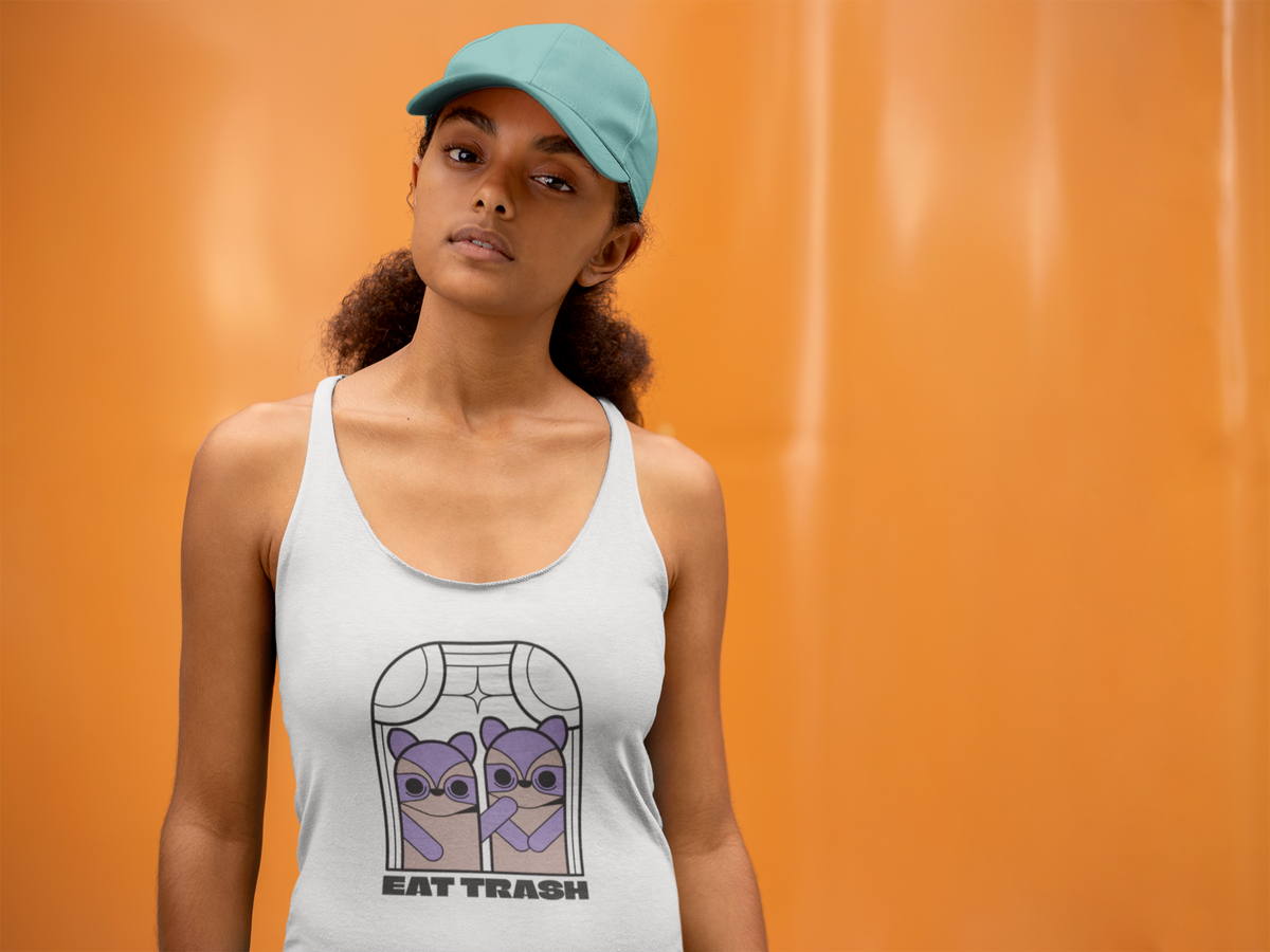 'Eat Trash' racerback tank top in white, woman wearing it by an orange wall, Tank Top mockup, Geekpsters