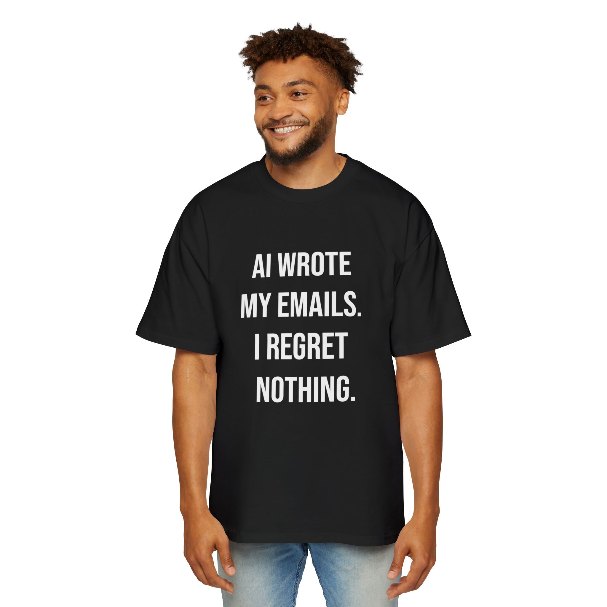 A man wearing the "AI WROTE MY EMAILS I REGRET NOTHING - Heavy Oversized Tee," made from 100% carded cotton in black, stands and smiles, showcasing bold sci-fi chic style.