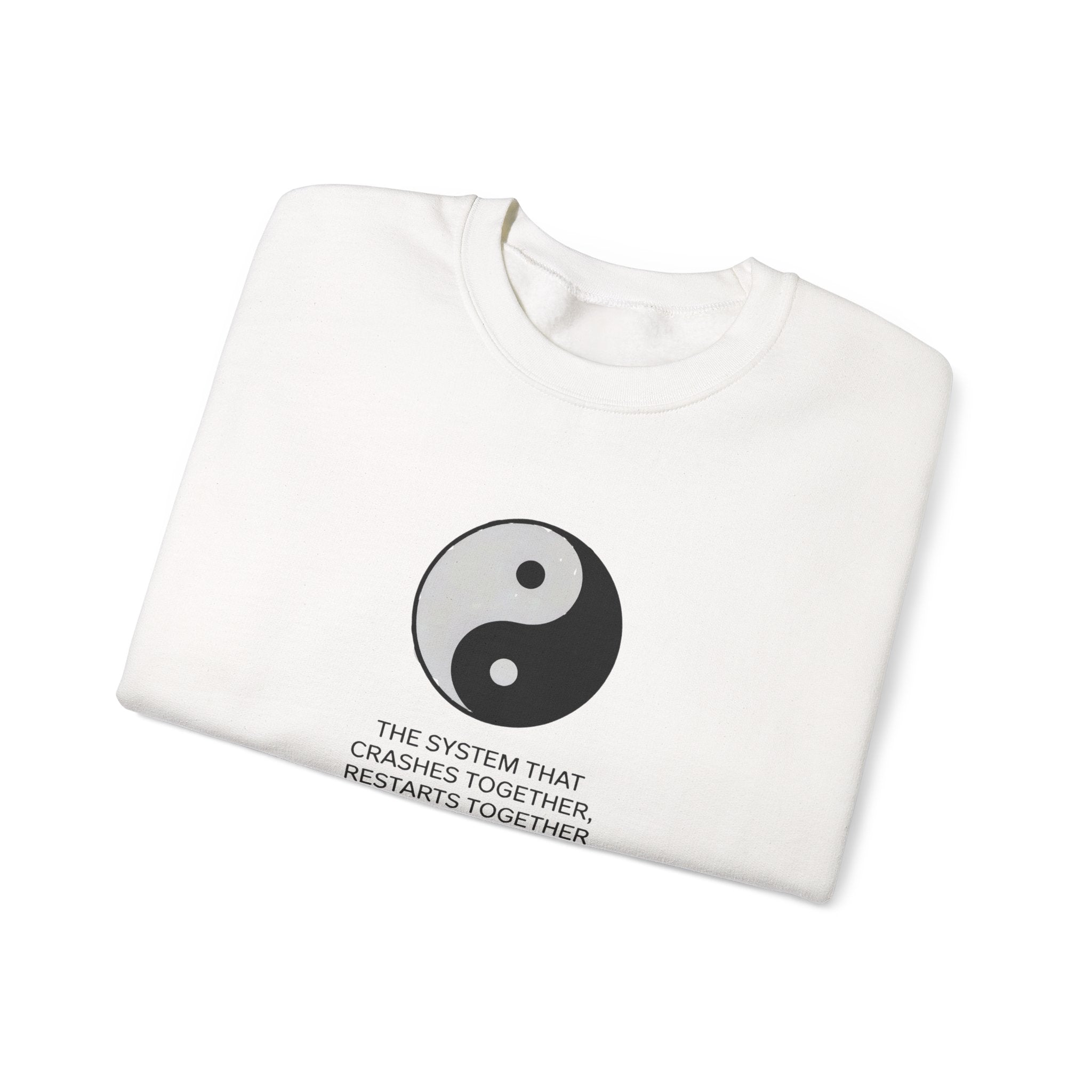The "A System That Crushes Together Restarts Together" sweatshirt is folded, white, and features a black-and-white yin-yang symbol with the phrase printed below.