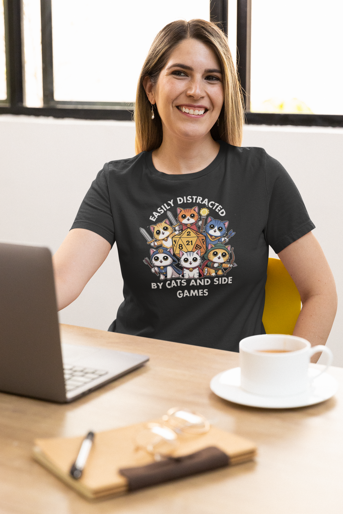 'Easily Distracted by Cats and Side Games' tee in black, woman wearing it at a desk, coder gift