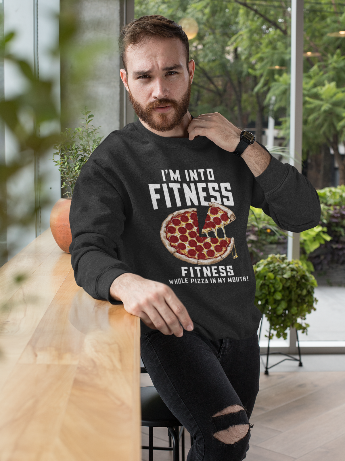 'I'm Into Fitness' pizza sweatshirt in black, bearded man wearing it while relaxing outdoors, funny pun gift