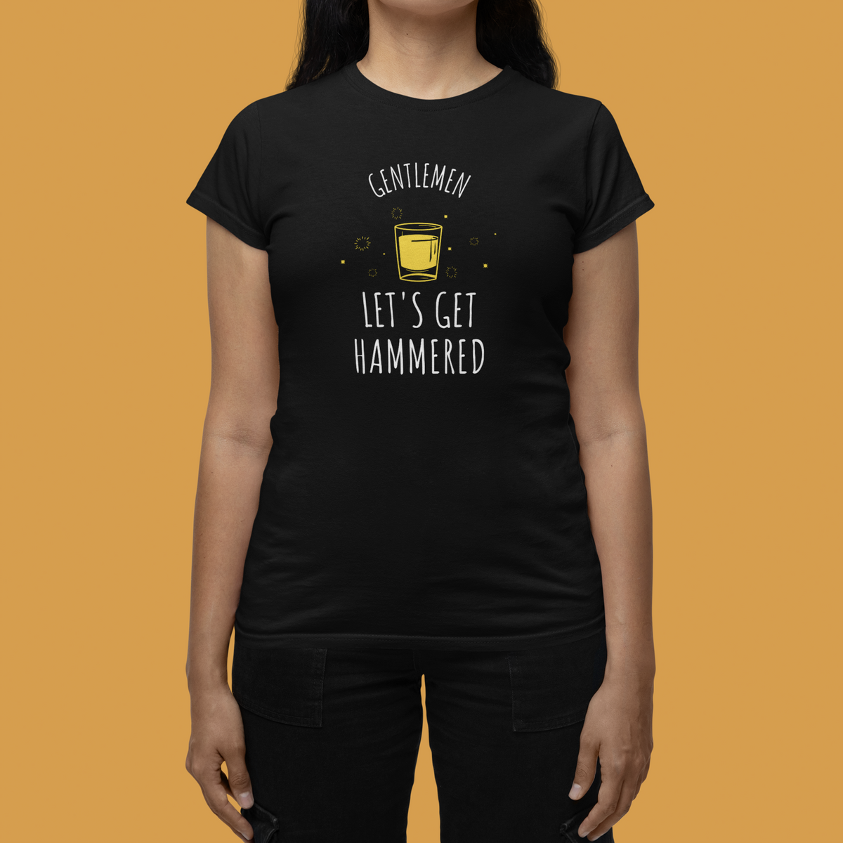 'Gentlemen Let's Get Hammered' women's t-shirt in black, close-up on model, orange backdrop, party gift
