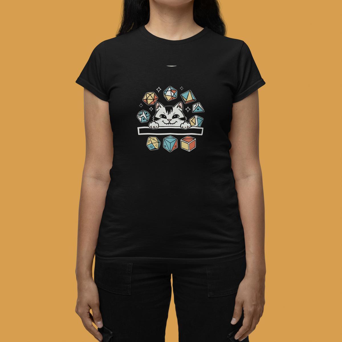 Cat Dice women's t-shirt in black, polyhedral dice and cat print, woman on mustard backdrop, tabletop gamer gift