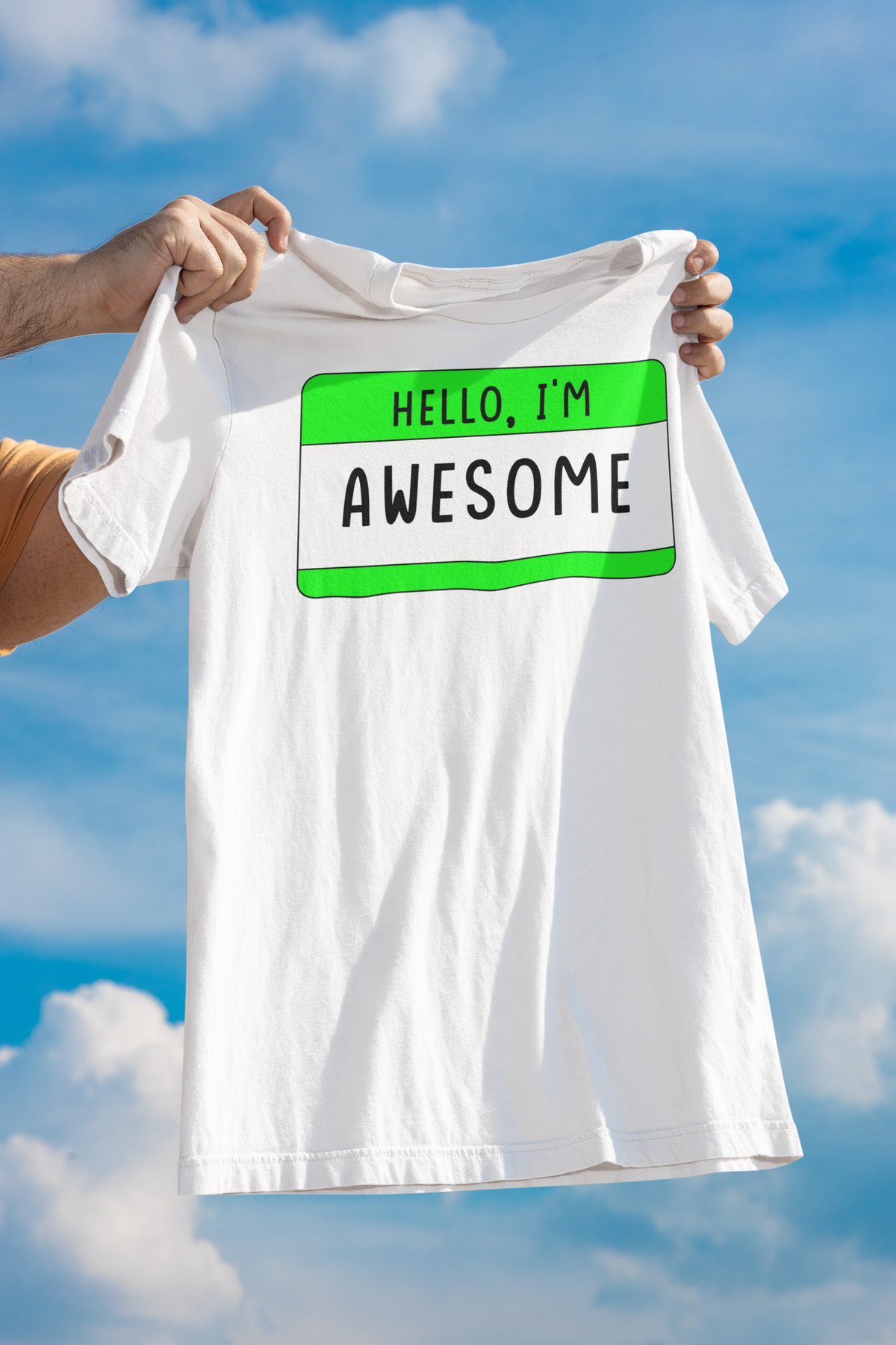 Hello I'm Awesome name tag T-shirt in white, man holding it up against a sky backdrop, confidence gift tee