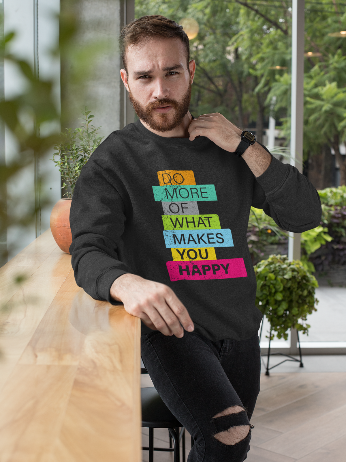 'Do More of What Makes You Happy' sweatshirt in black, bearded man wearing it outdoors, uplifting gift