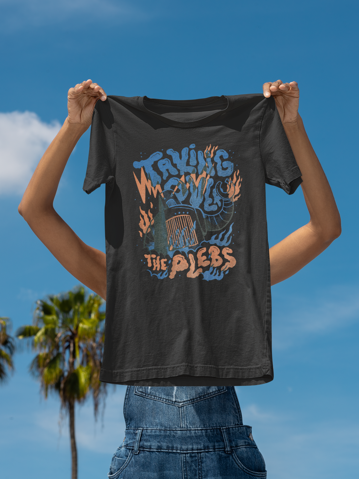 'Taking Over The Place' t-shirt in black, held up outdoors under a blue sky