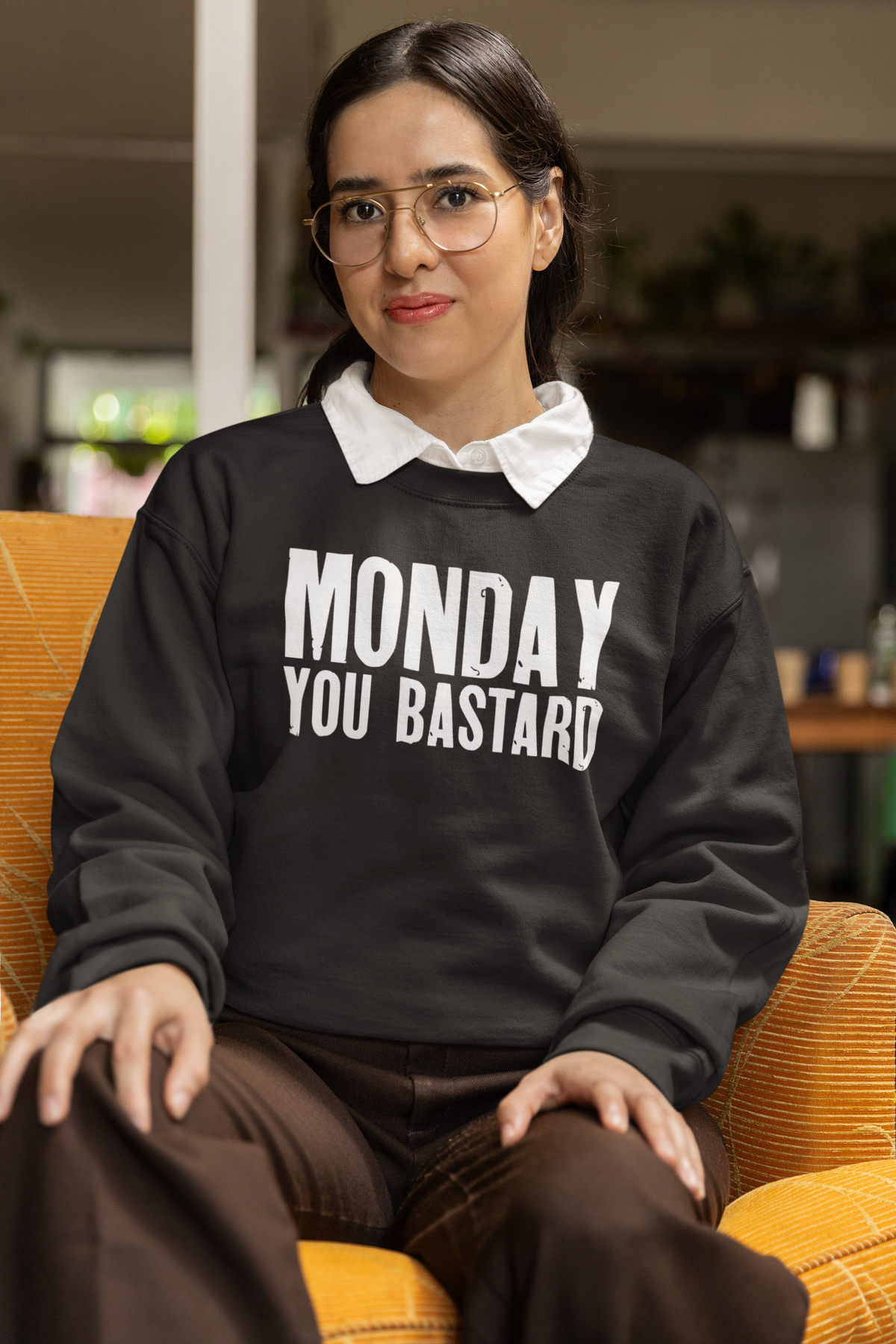 'Monday You Bastard' text sweatshirt in black, woman sitting indoors in an armchair, funny sarcastic gift