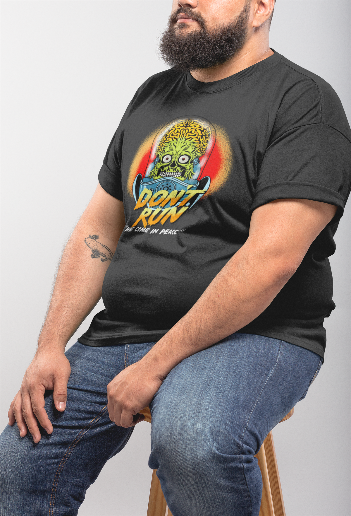'Don't Run' alien t-shirt in heather black, seated bearded man wearing it, funny alien gift