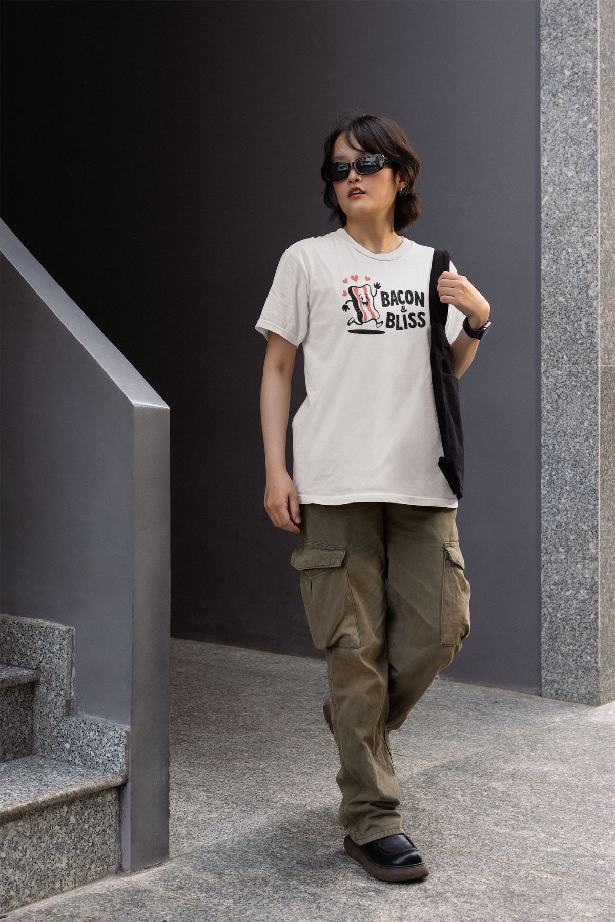 'Bacon & Bliss' womens tee in white with bacon character print, woman walking outdoors, funny bacon lover gift