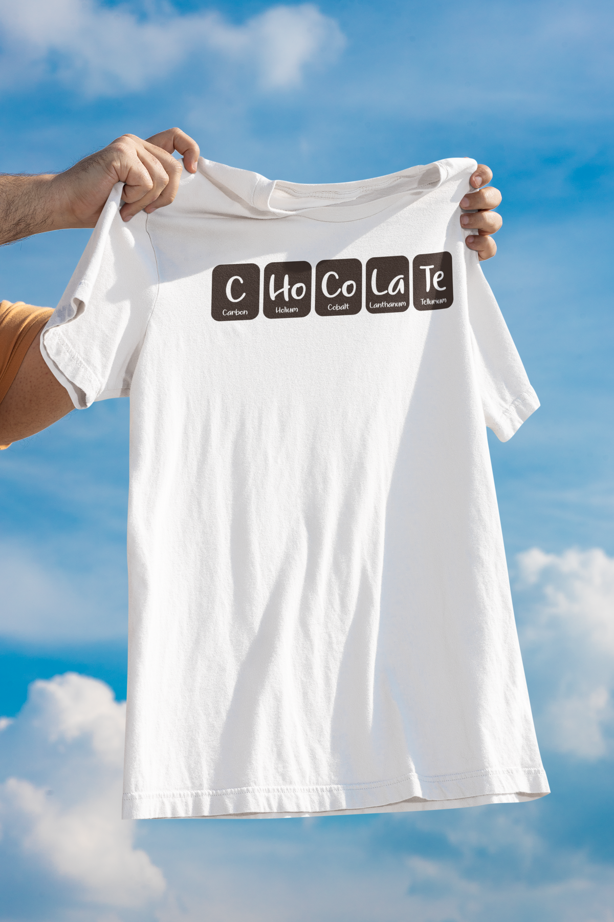 "Chocolate" periodic table t-shirt in white, hand holding it up outdoors, quirky chemistry gift for chocolate fans