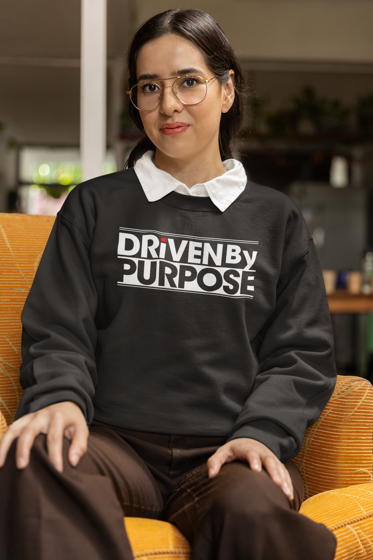 Driven by Purpose Sweatshirt in black, woman sitting indoors wearing it, motivational streetwear gift