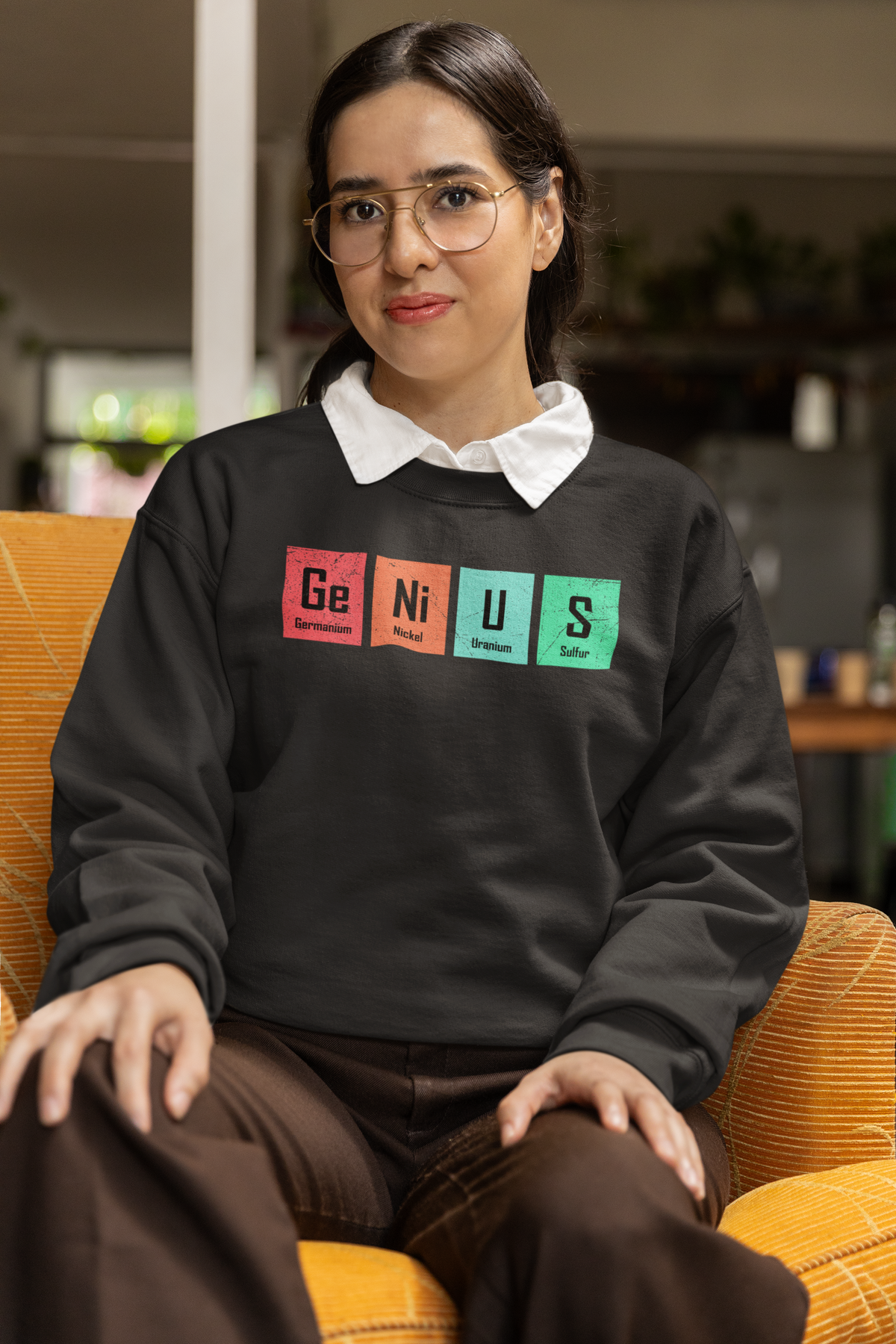 'Genius' periodic table pun sweatshirt in black, woman sitting indoors, funny science sweatshirt gift
