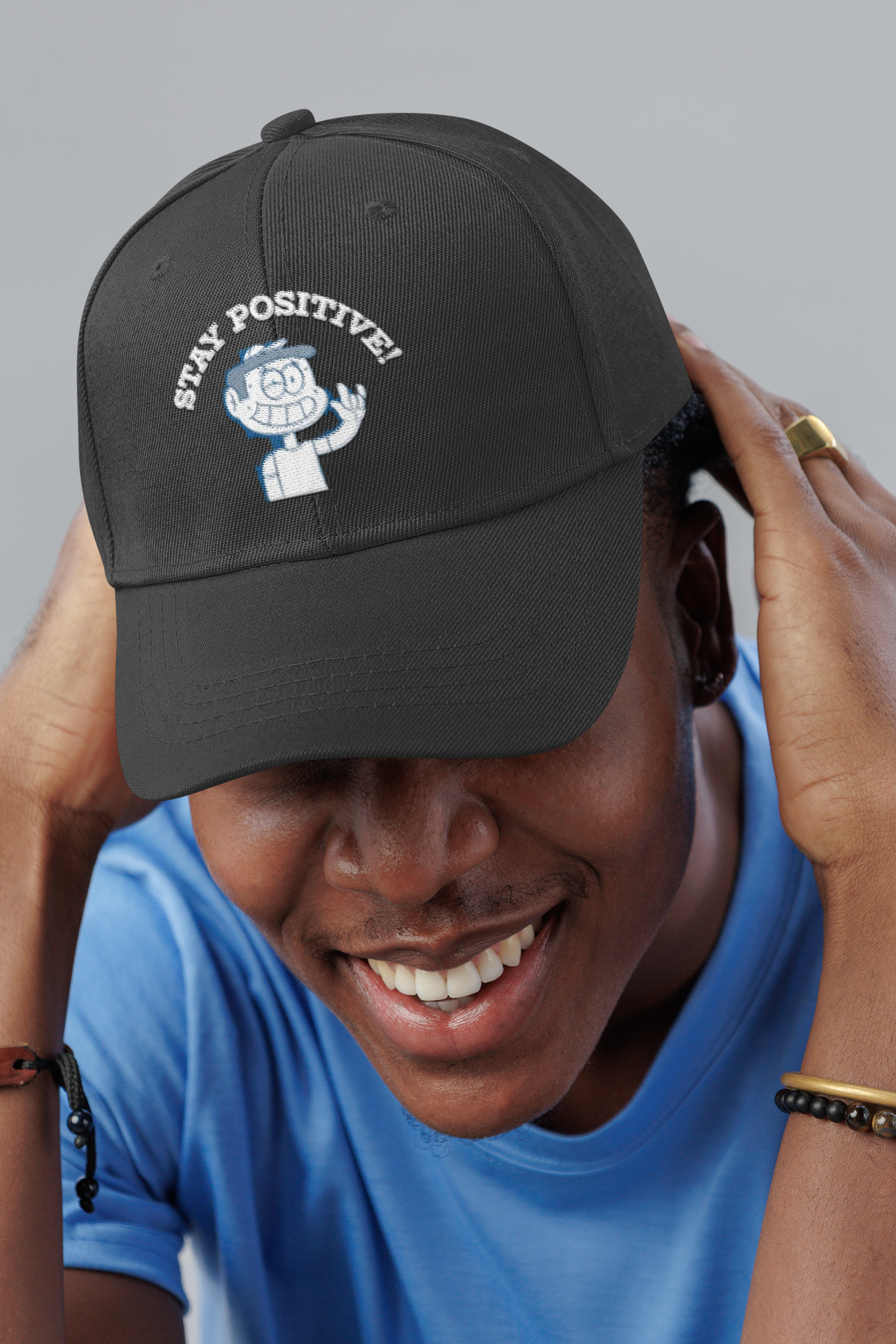 Stay Positive embroidered dad hat worn by a smiling man in a studio, lifestyle mockup, Geekpsters