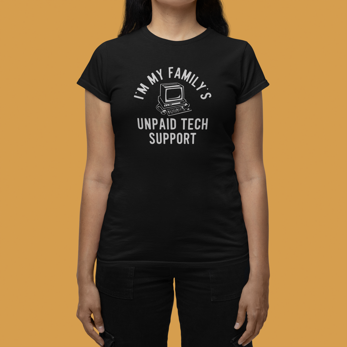 'I'm My Family's Unpaid Tech Support' womens tee in black, woman wearing it on mustard background, IT gift