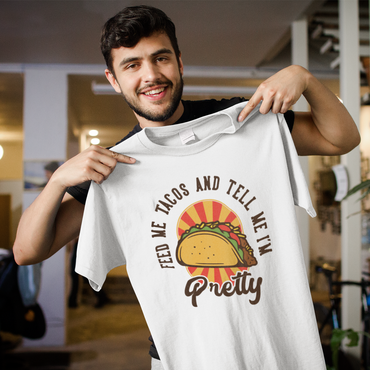 'Feed Me Tacos and Tell Me I'm Pretty' t-shirt in white, man holding it up showing taco print, foodie gift