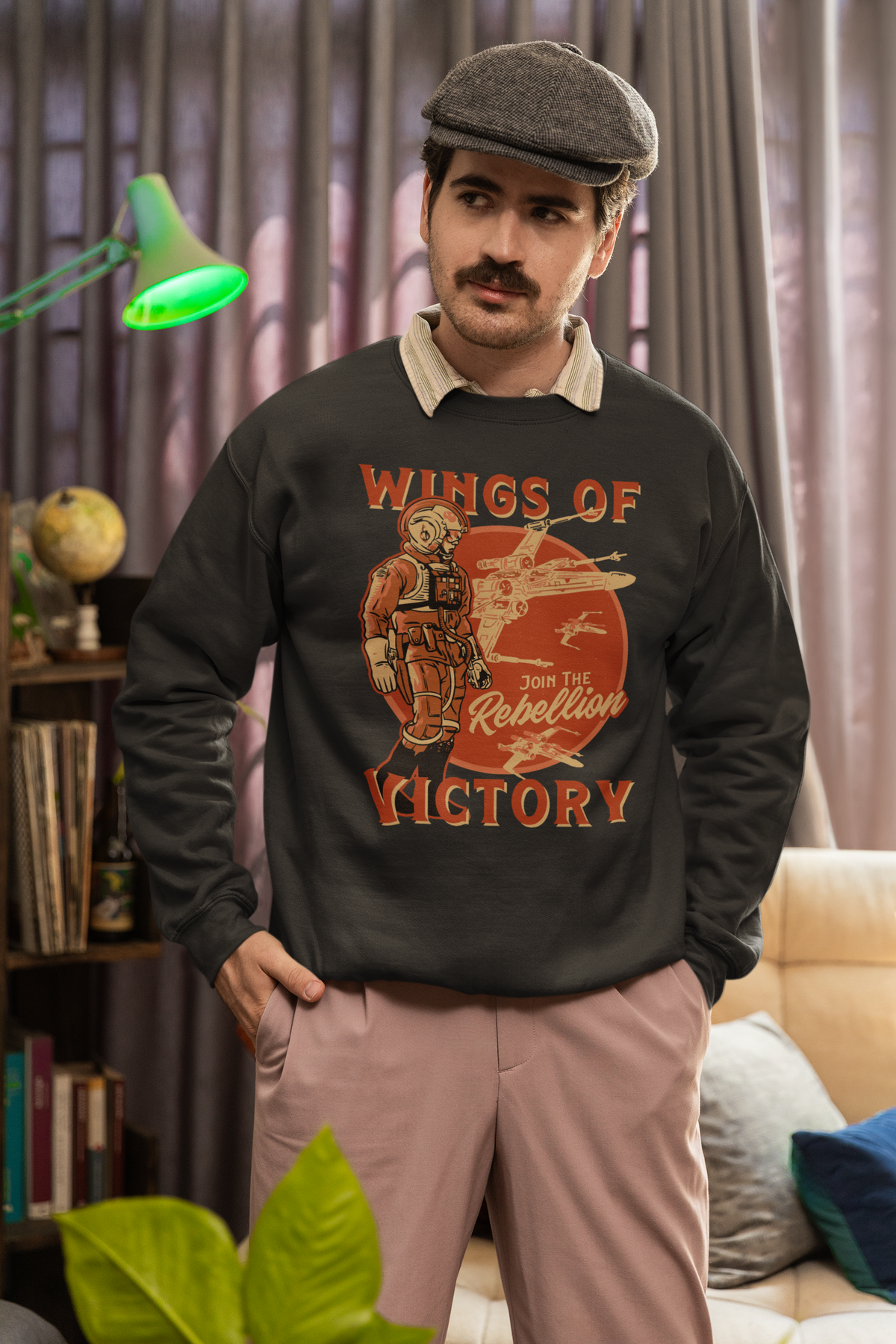 'Wings of Victory' sweatshirt in charcoal heather, man wearing it indoors, rebel warrior crewneck gift