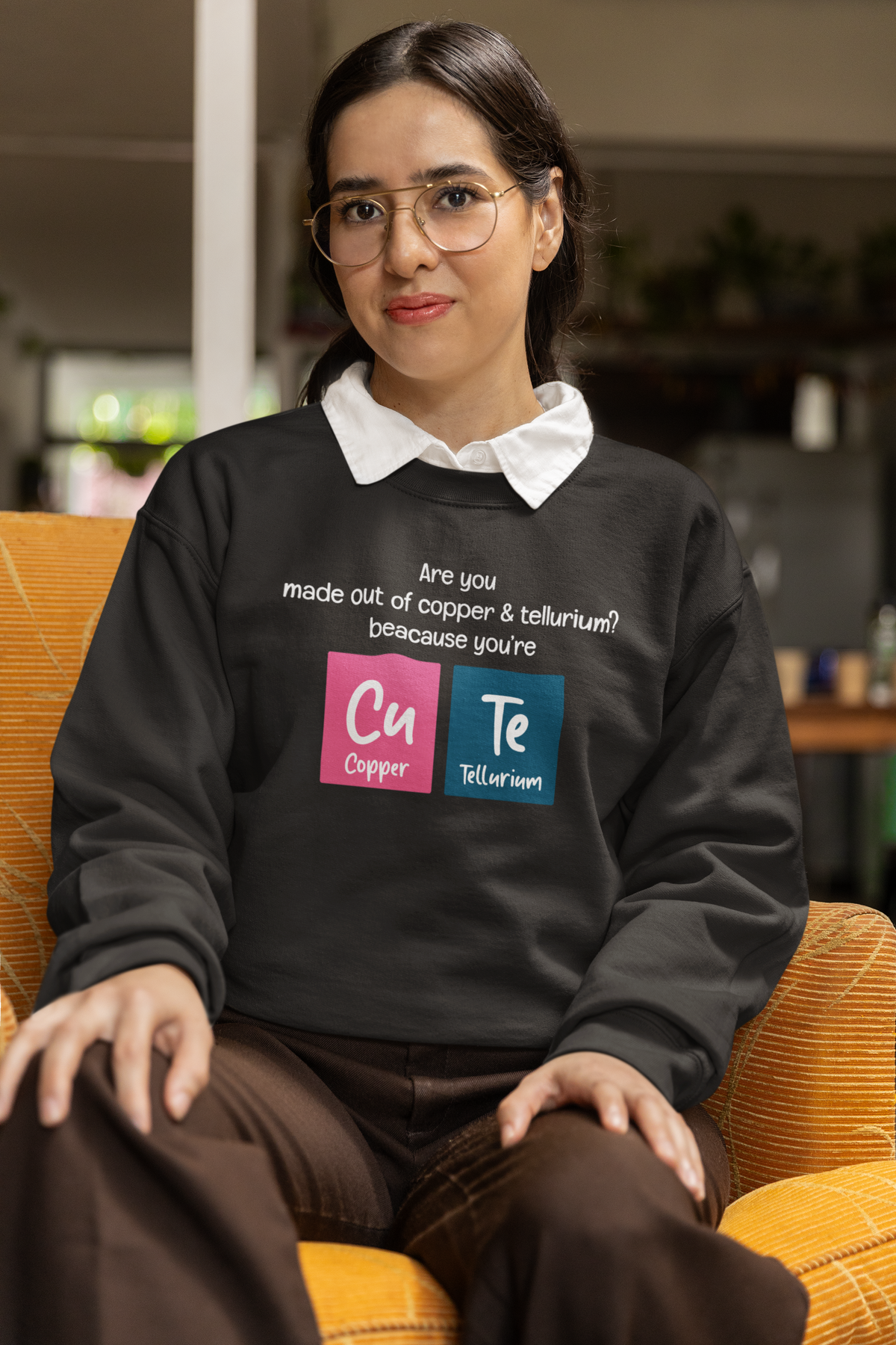 Cu-Te periodic table cute pun crewneck sweatshirt in black, model wearing it indoors with the graphic shown