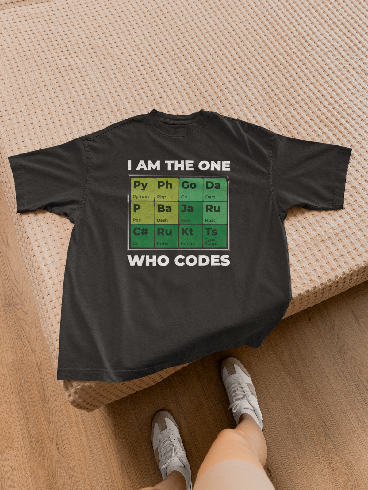 "I Am The One Who Codes" periodic table tee in black, close-up on wood surface, funny developer gift