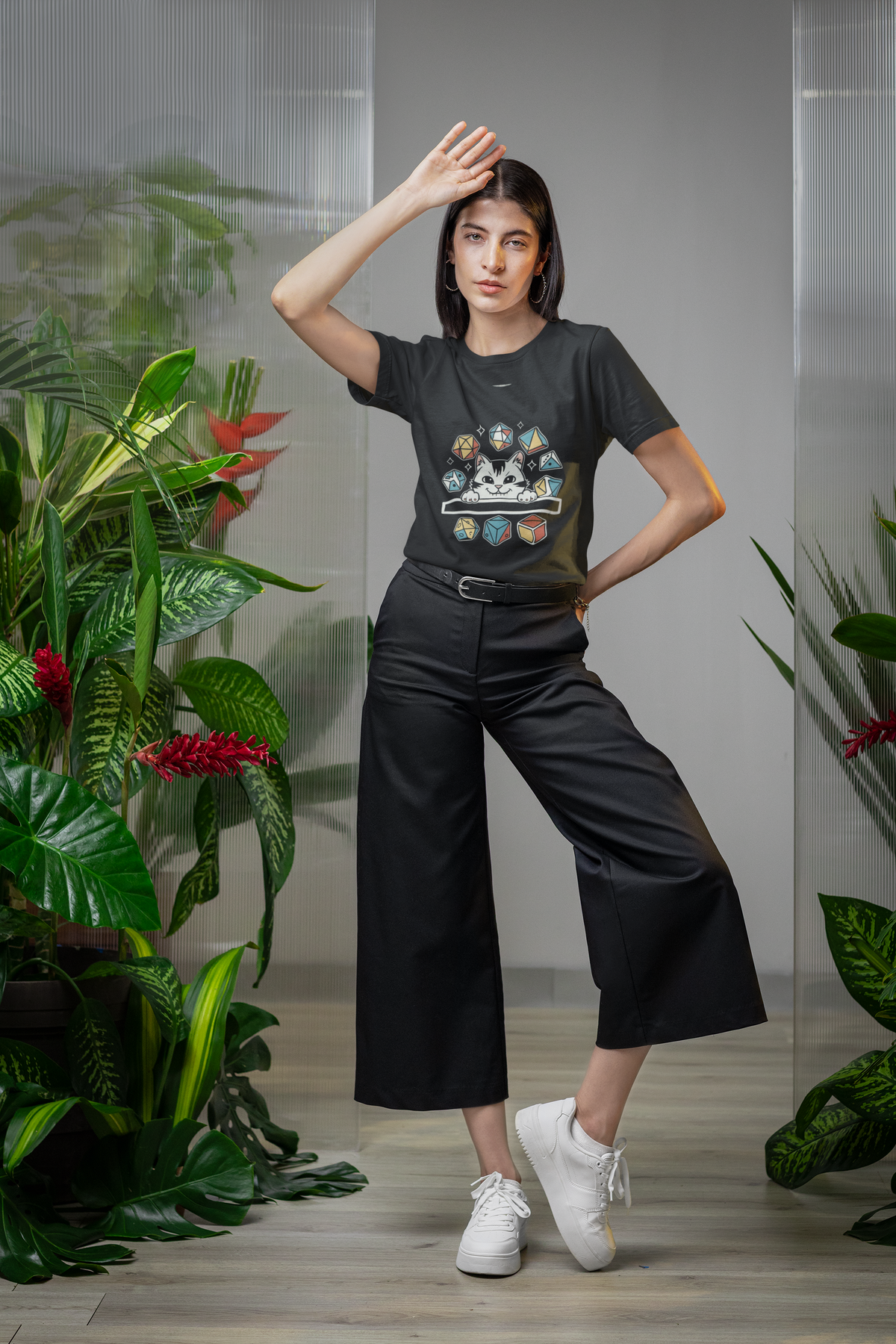 'Cat Dice' t-shirt in black, woman wearing it in a plant-filled studio, funny tabletop RPG tee gift