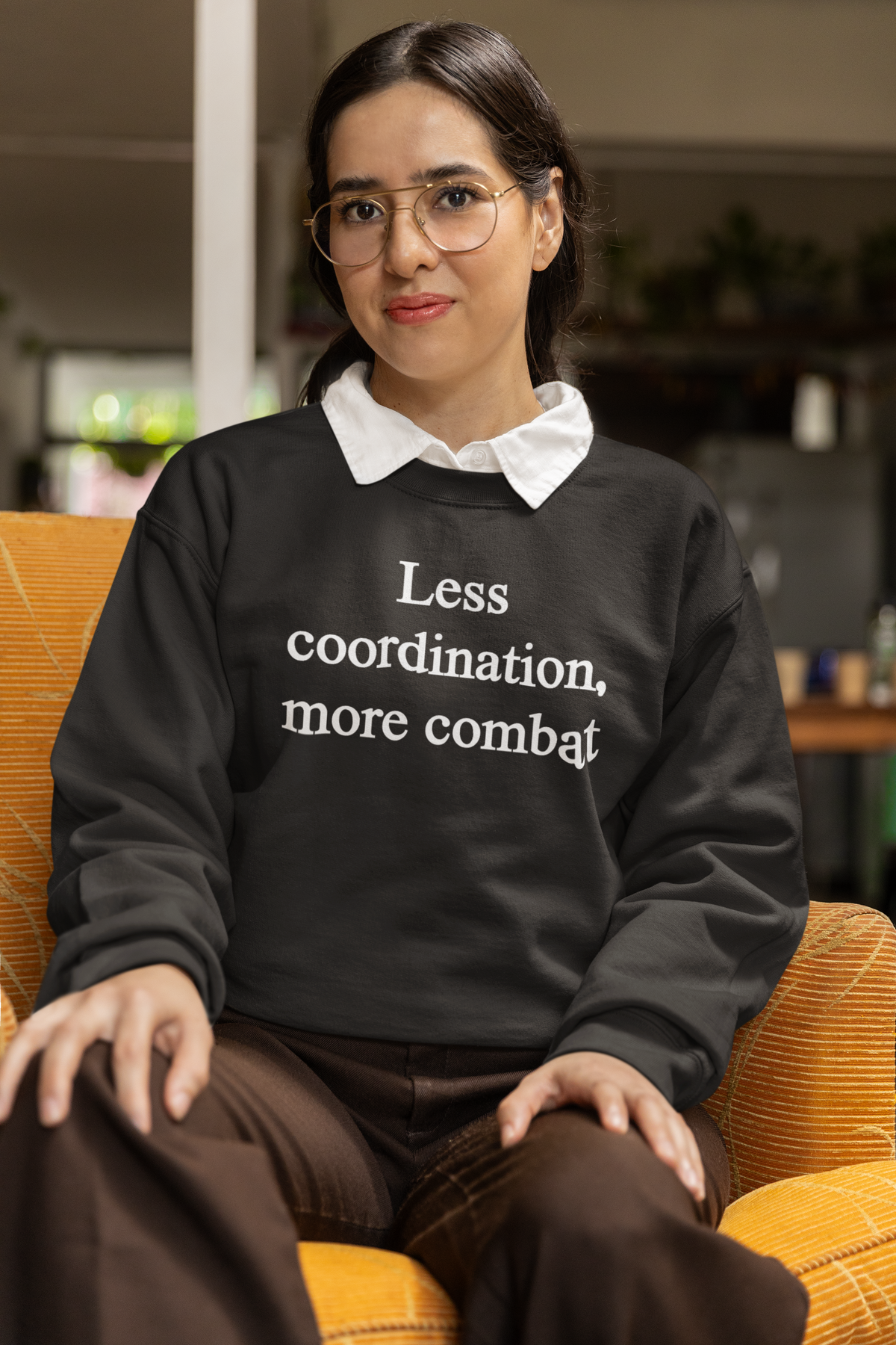 'Less Coordination More Combat' sweatshirt in black, woman modeling it indoors, funny sarcastic gift