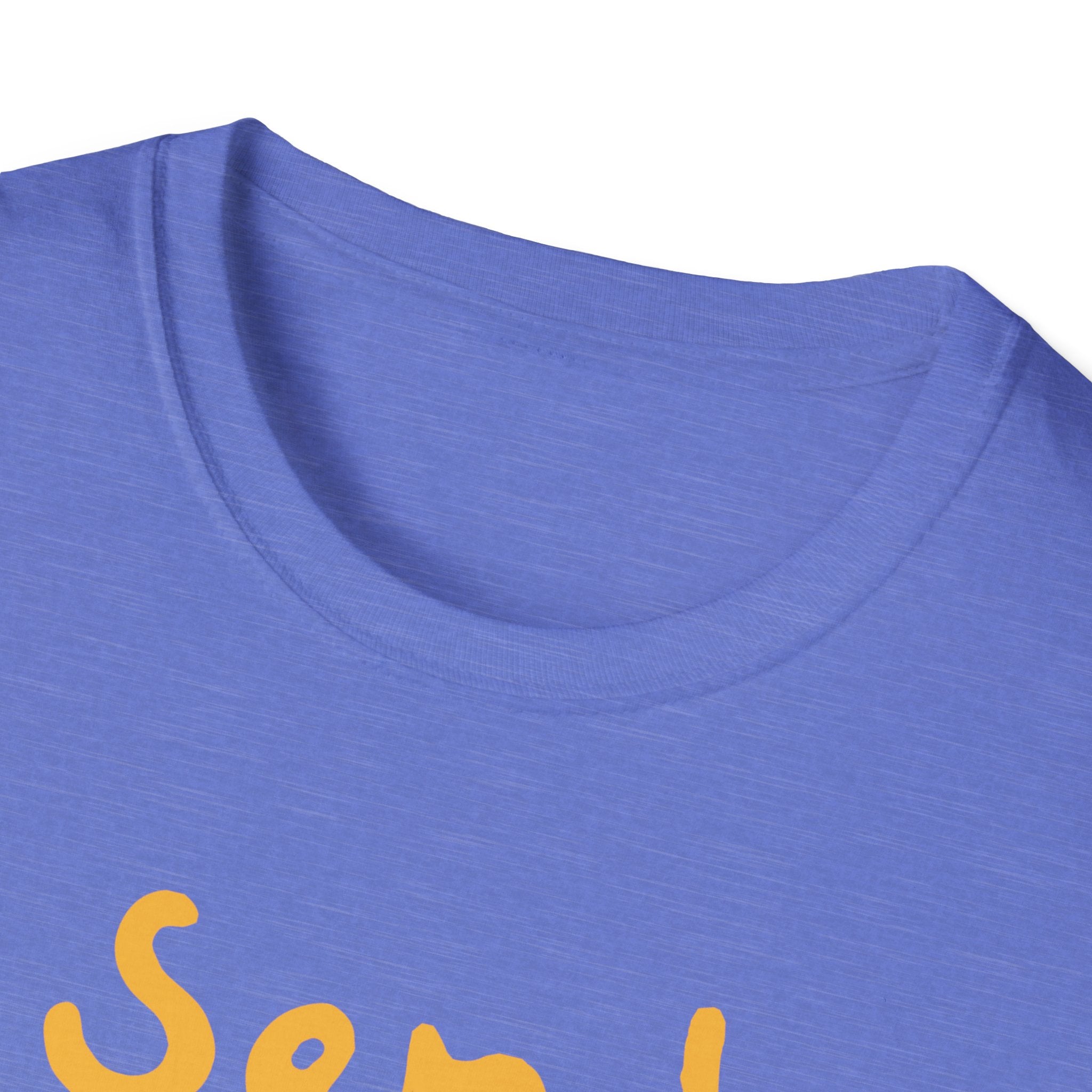 A close-up of the Send Noods T-Shirt shows its blue fabric with partially visible yellow text on the front that begins with "Sen." The shirt, featuring the playful "Send Noods" phrase, is displayed against a plain white background to emphasize its trendy fit.