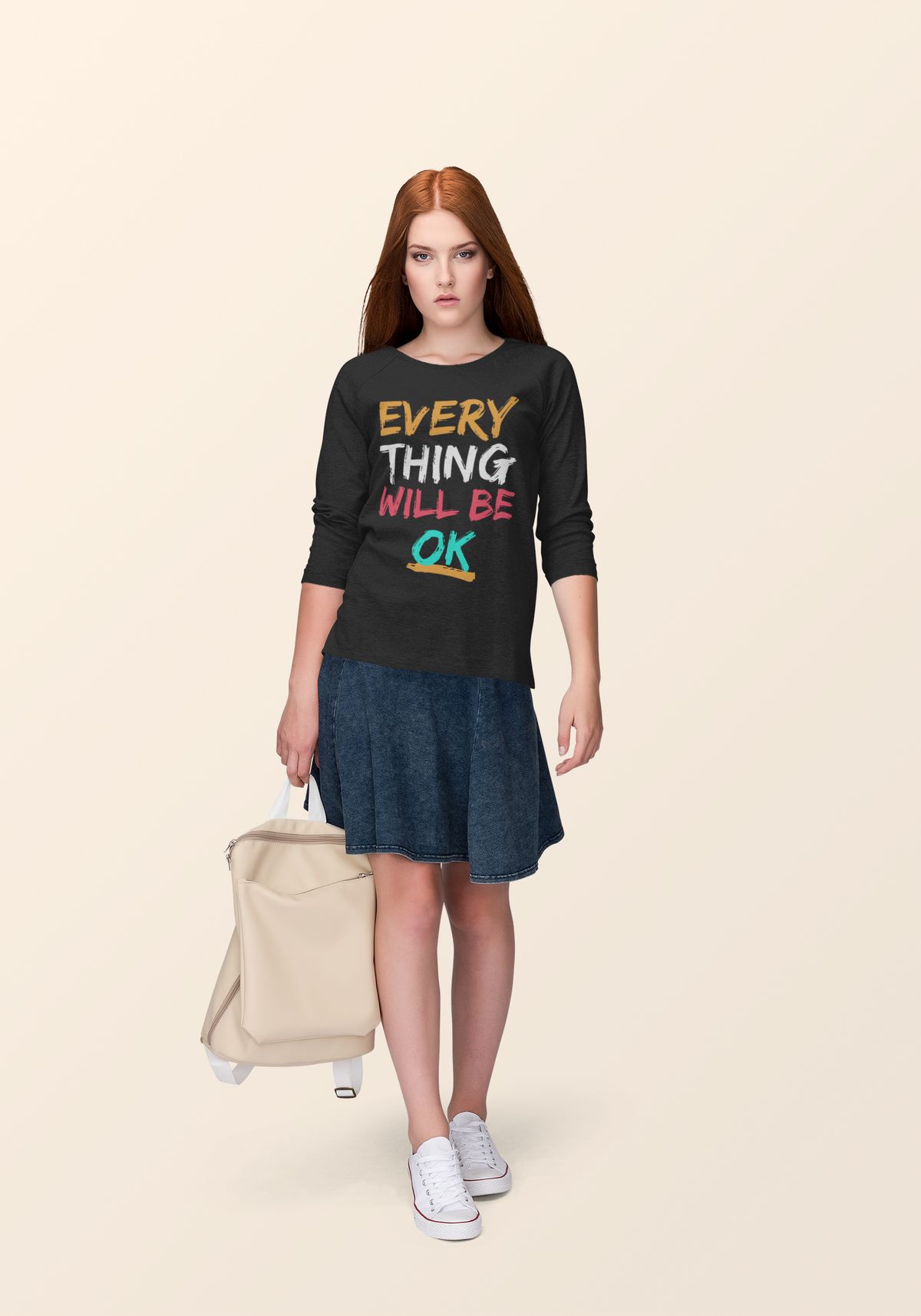 'Everything Will Be OK' sweatshirt in black, woman wearing it in a travel scene with a suitcase